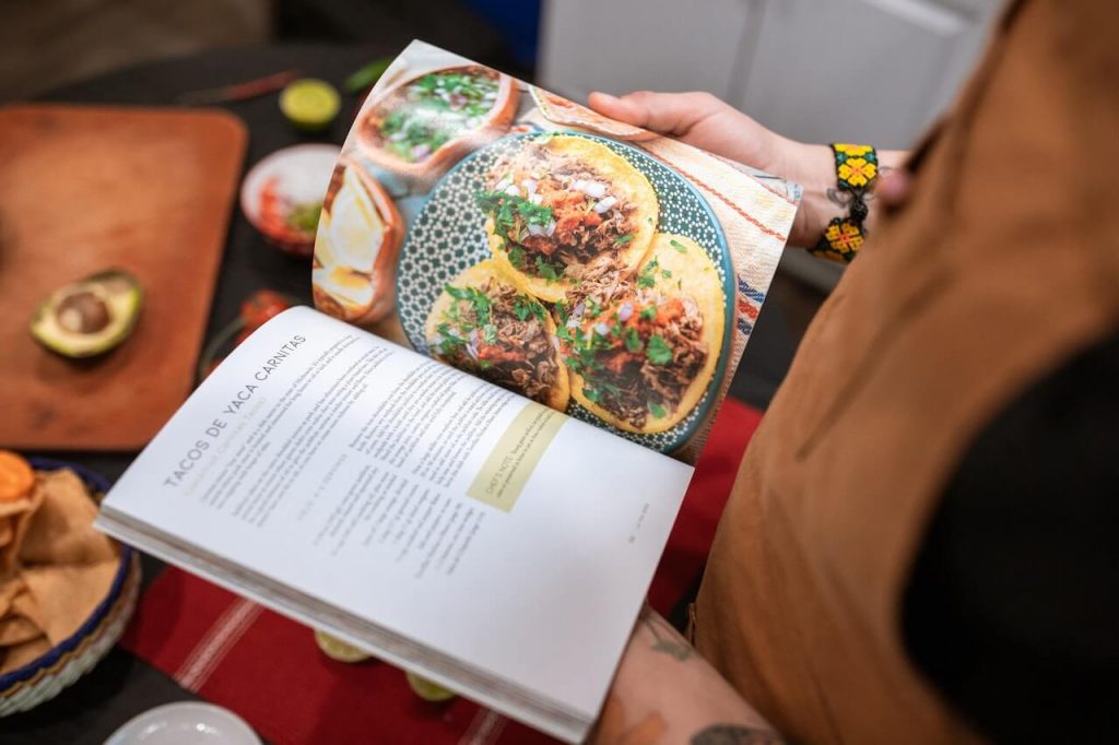 Une personne absorbée par la lecture d'un livre de cuisine, étudiant les recettes et recueillant l'inspiration culinaire.