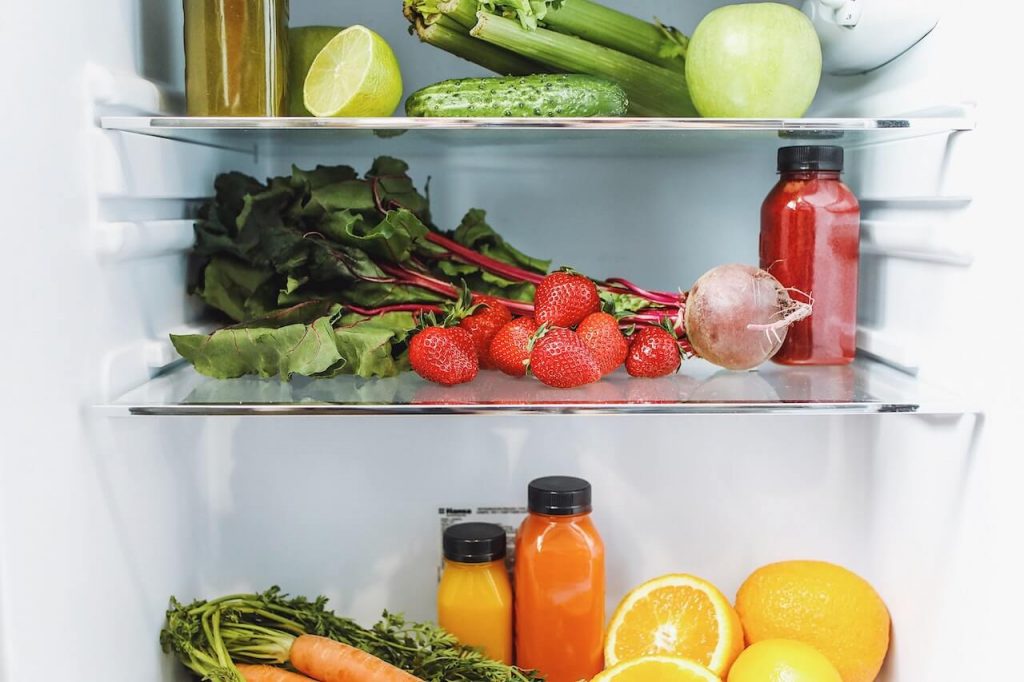 Un réfrigérateur rempli d'un assortiment de légumes et de fruits éclatants, bien rangés et prêts à être consommés.